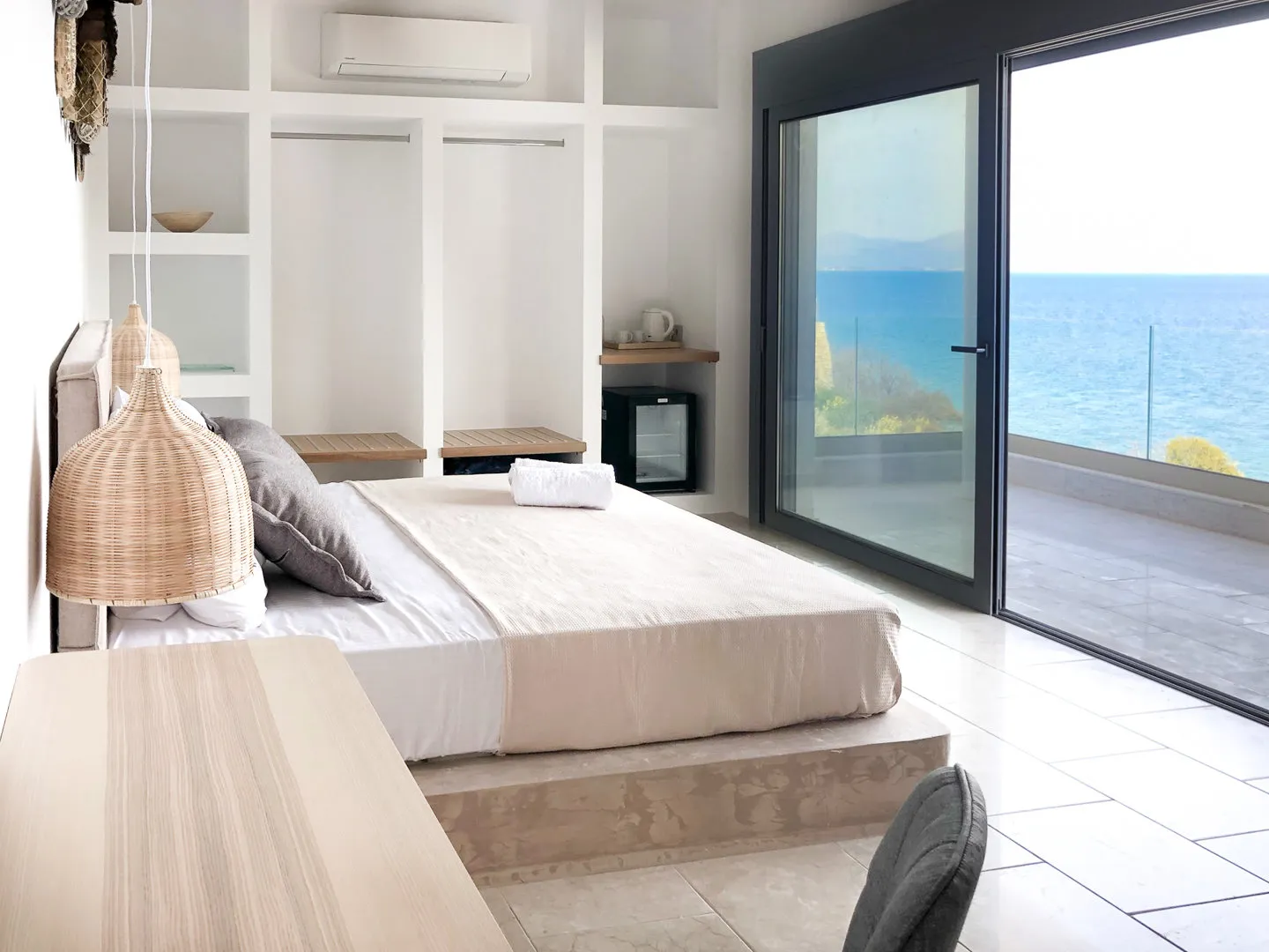 Zephyros-Schlafzimmer mit offenen Regalen und Glastüren zur Terrasse mit Meerblick