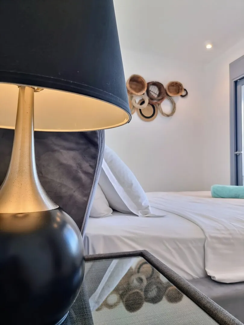 Tischlampe und Flechtdekor neben dem Bett von Eos