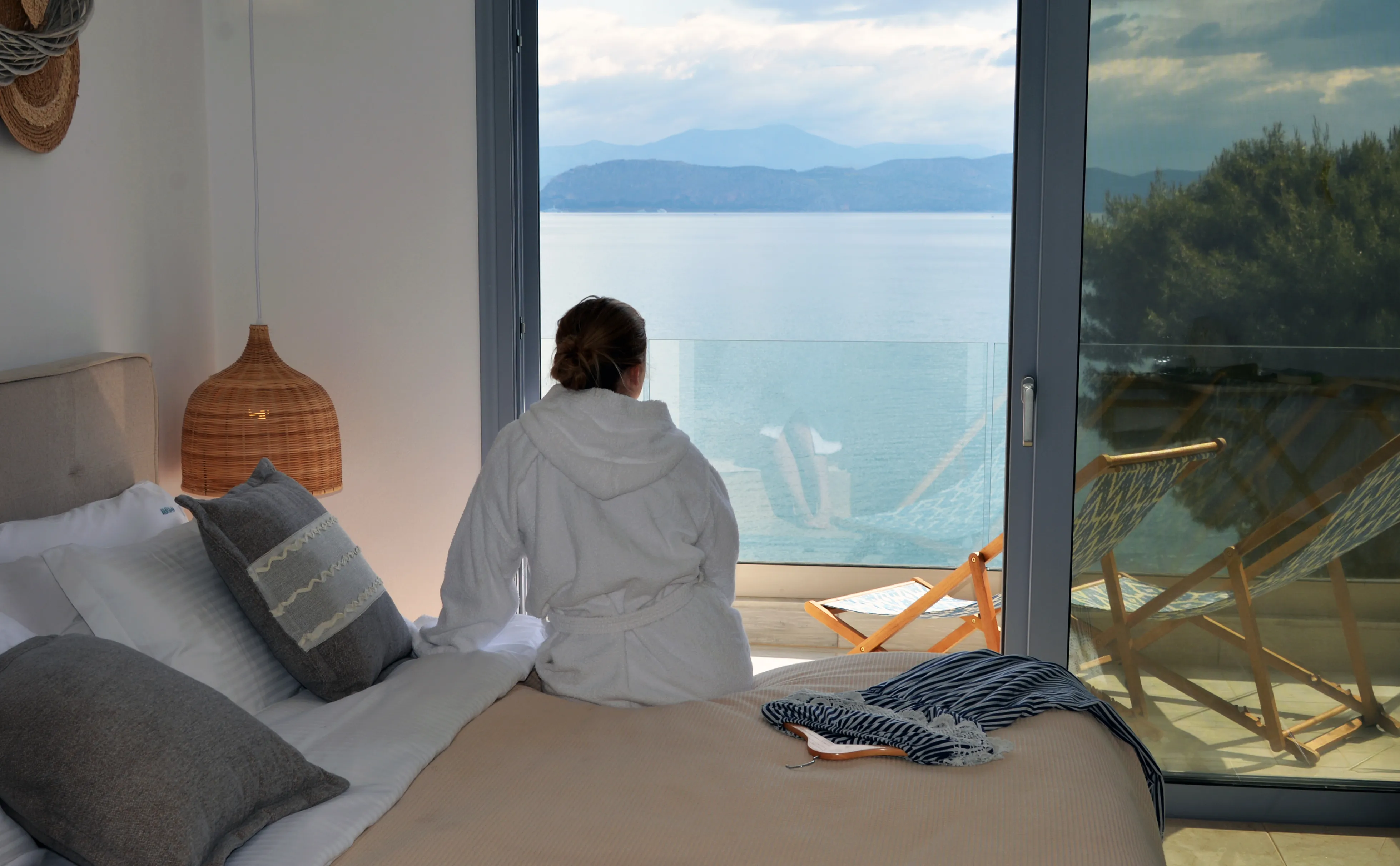 Gast auf dem Bett mit Blick durch die offene Glastür auf das Meer
