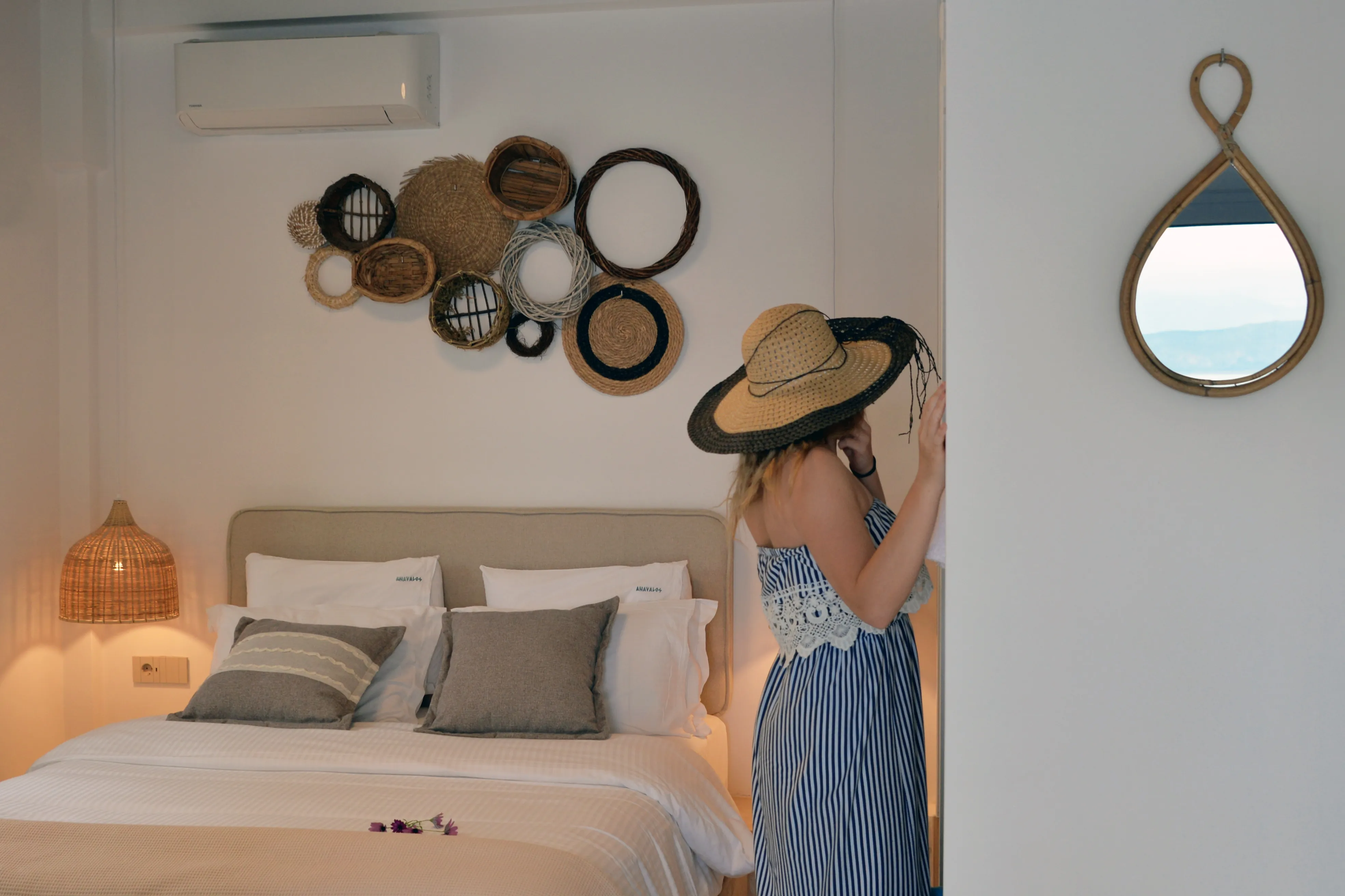 Notos-Schlafzimmer mit geflochtenen Wandkörben und Gast mit Sonnenhut