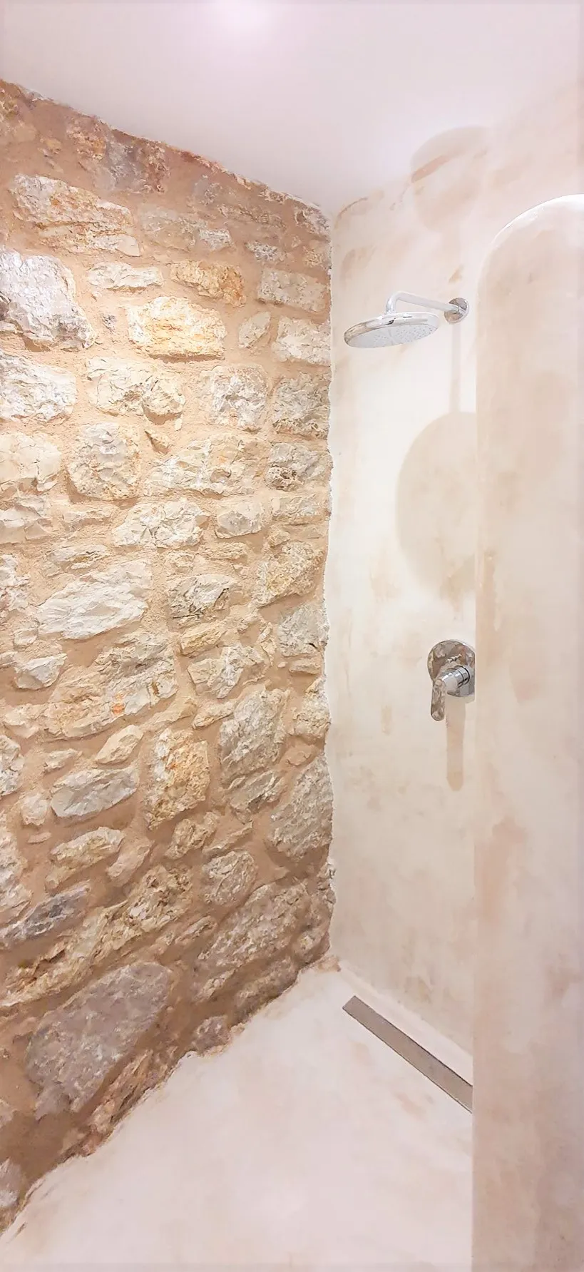 Ντους με πέτρινο τοίχο και γυαλιστερά εξαρτήματα