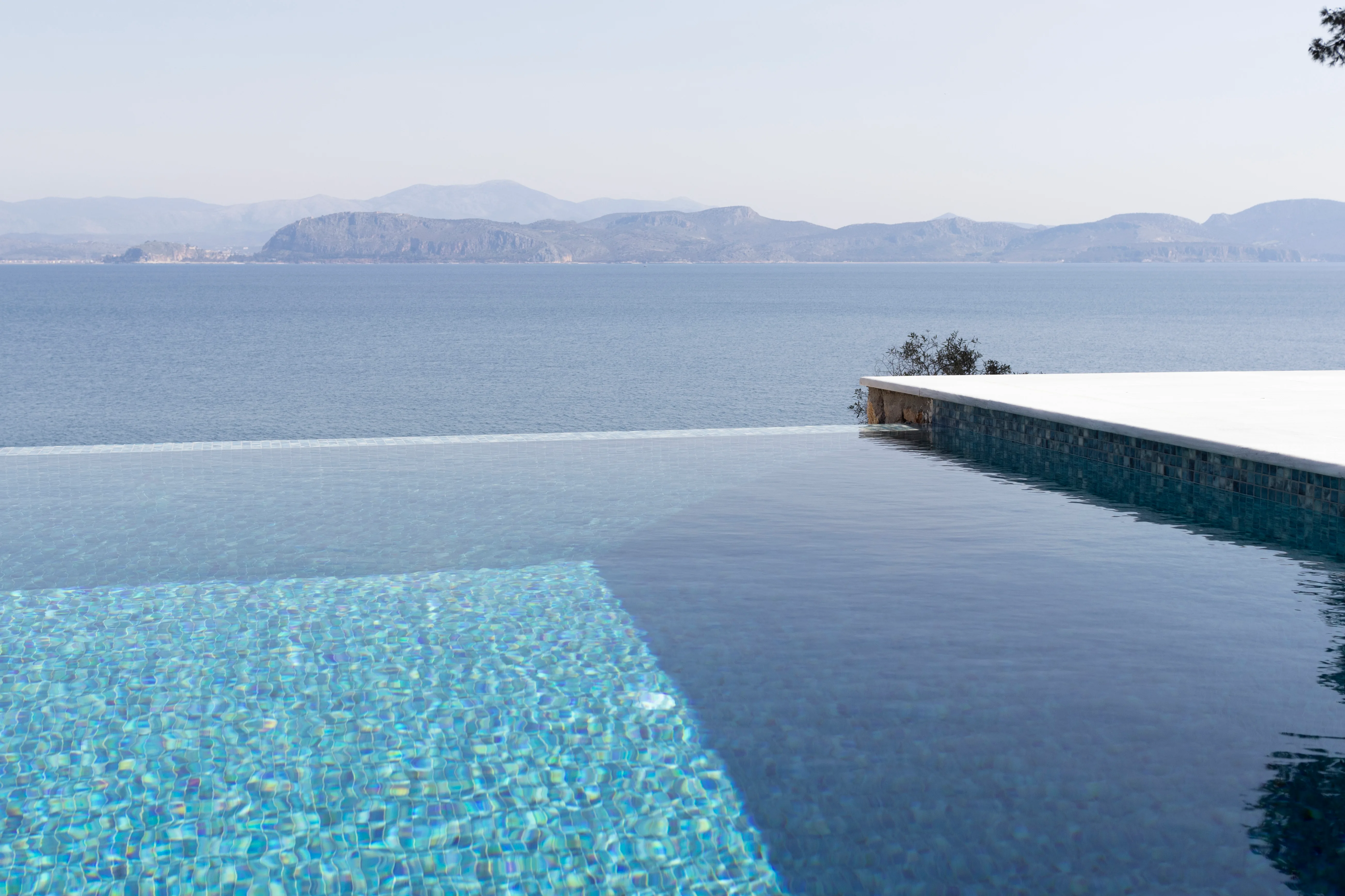 Ecke des Mosaik-Infinity-Pools über dem offenen Golf